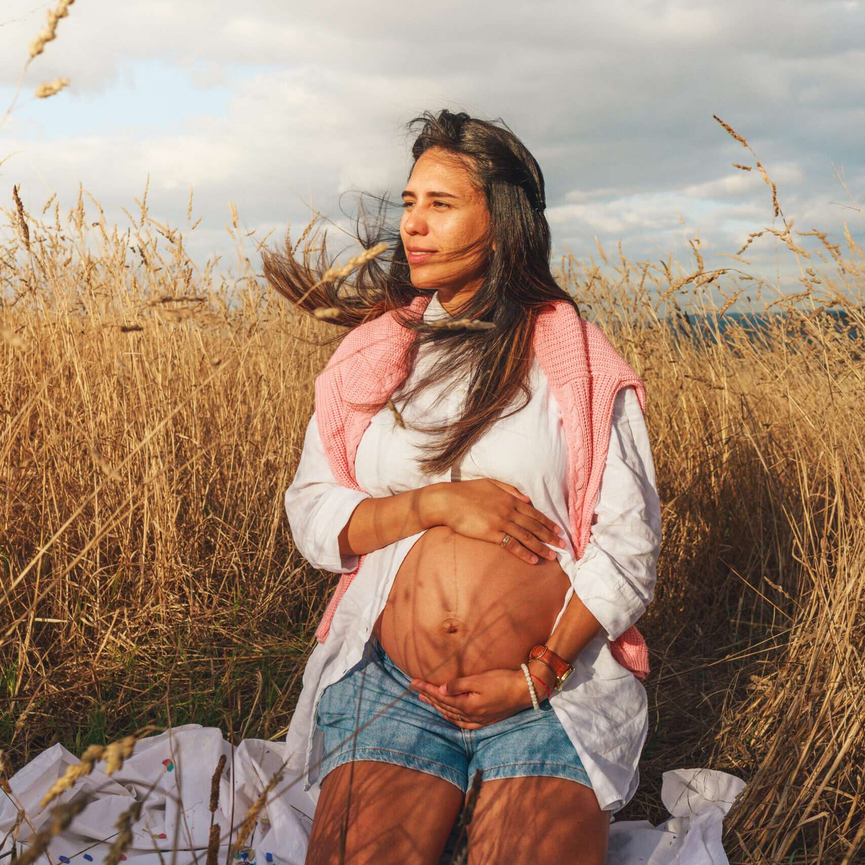 Young pregnant woman seated on a wheat field Young pregnant woman seated on a wheat field
